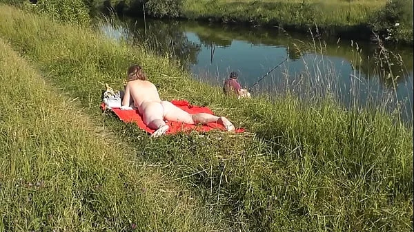 MILF sexy Frina on river bank undressed and sunbathes naked. Random man fisherman watching for her, and in the end decided to join naked woman. Wild beach. Nudist beach. Public nudity. Public exposure. Naked in public